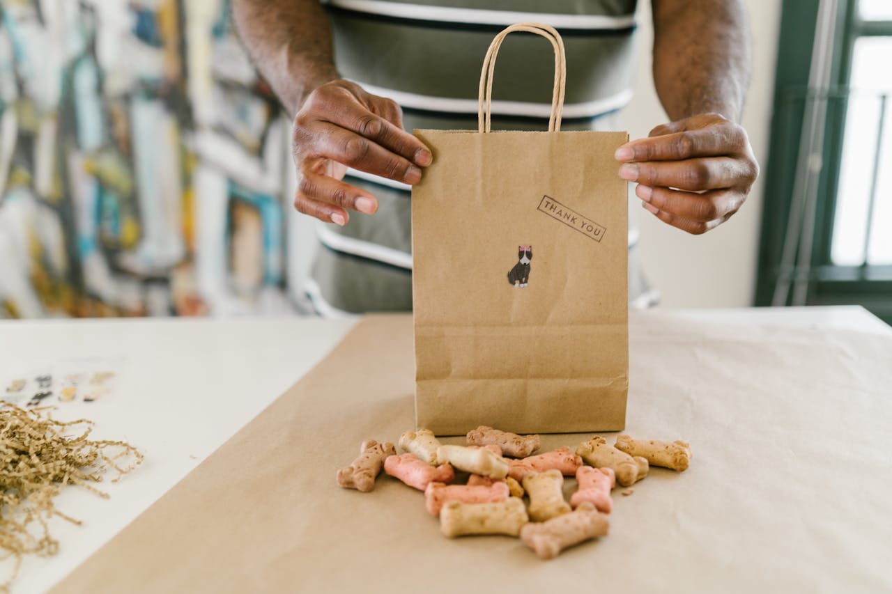 Services-03 Hands pack colorful dog treats in a thank you kraft paper bag.
